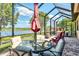 Relaxing screened-in patio with dining set, lounge chairs, and beautiful water views, perfect for outdoor enjoyment at 23494 Copperleaf Dr, Venice, FL 34293