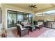 Relaxing screened patio featuring comfortable wicker furniture, an outdoor kitchen, and serene water views at 23494 Copperleaf Dr, Venice, FL 34293