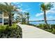 Scenic lakeside walkway lined with lush landscaping and palm trees under a blue sky at 23494 Copperleaf Dr, Venice, FL 34293