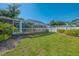 Beautiful backyard featuring a screened lanai, lush green lawn, and meticulously maintained landscaping at 23516 Peachland Blvd, Port Charlotte, FL 33954