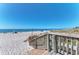 View of a white sand beach from a wooden walkway, showing beachgoers and umbrellas at 23516 Peachland Blvd, Port Charlotte, FL 33954