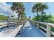 Wooden boardwalk with railings leads to the beach and surrounding tropical foliage at 23516 Peachland Blvd, Port Charlotte, FL 33954