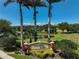 Inviting entrance to Suncoast Lakes featuring manicured landscaping, mature palms, and tranquil pond views at 24477 Lakeside Mnr, Punta Gorda, FL 33980