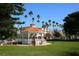 Scenic park view featuring a gazebo with red benches and palm trees, with commercial buildings in the background at 264 Caserta Ct, Nokomis, FL 34275