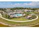 Scenic aerial view of community pool, tiki huts, clubhouse, and surrounding residential homes near lake at 268 Ibiza Loop, Venice, FL 34292