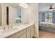 Bright bathroom featuring double sinks, a large mirror, and a view into the bedroom at 268 Ibiza Loop, Venice, FL 34292