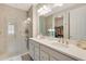 Modern bathroom with dual sinks, a large mirror, and a glass-enclosed shower at 268 Ibiza Loop, Venice, FL 34292