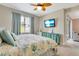 Comfortable bedroom with leaf-patterned bedding and a flat-screen television mounted on the wall at 268 Ibiza Loop, Venice, FL 34292