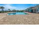 Inviting community pool with surrounding brick paved area, lounge chairs, and tiki huts at 268 Ibiza Loop, Venice, FL 34292