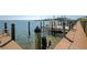 Waterfront view of a wooden dock with pilings, a boat lift, and a boat docked in the water at 2955 N Beach Rd # A422, Englewood, FL 34223