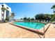 Community pool surrounded by lounge chairs and palm trees on a sunny day with clear blue skies at 2955 N Beach Rd # A422, Englewood, FL 34223