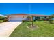 Charming single-story home with a well-manicured lawn, an attached garage, and a vibrant red tile roof at 322 Oakwood Cir, Englewood, FL 34223