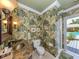 Stylish bathroom with tropical wallpaper, decorative mirror, and a glass-enclosed shower at 337 Harbor S Dr, Venice, FL 34285