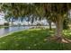 Scenic lakeside area with picnic benches, lush grass, and a large shade tree, perfect for outdoor relaxation and gatherings at 379 Harbor Isles Dr, North Port, FL 34287