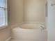 A bathroom featuring a large soaking tub with tile surround and window to the left at 4062 Green Tree Ave, Sarasota, FL 34233