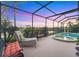 Outdoor screened-in pool area with a lake view, lounge chairs and a spa at 4326 Corso Venetia Blvd, Venice, FL 34293