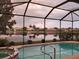 Enclosed pool and spa overlook the tranquil lake with beautiful landscaping and community homes in the background at 4326 Corso Venetia Blvd, Venice, FL 34293