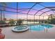 Screened-in pool and spa overlooking a serene lake at sunset, perfect for relaxation and entertaining at 4326 Corso Venetia Blvd, Venice, FL 34293
