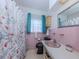 Retro pink bathroom with floral shower curtain and black toilet at 444 Driftwood Rd, Venice, FL 34293