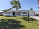 Charming home featuring a well-manicured lawn and a beautiful palm tree, creating a welcoming tropical ambiance at 444 Driftwood Rd, Venice, FL 34293