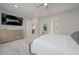 Light-filled bedroom featuring a mounted TV, ensuite bathroom, and a large dresser at 5632 Long Shore Loop, Sarasota, FL 34238
