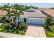 Charming single-Gathering home featuring a brick driveway, two-car garage, and tropical landscaping at 5632 Long Shore Loop, Sarasota, FL 34238