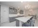 Open kitchen with gray cabinets, oversized island with bar seating, pendant lighting, and bright marble floors at 5632 Long Shore Loop, Sarasota, FL 34238