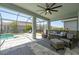Relaxing covered patio featuring a ceiling fan, comfortable seating, and views of the screened pool at 5632 Long Shore Loop, Sarasota, FL 34238