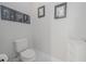 Simple powder room with toilet and framed artwork in neutral colors at 5632 Long Shore Loop, Sarasota, FL 34238