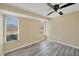 Bedroom with neutral walls, wood-look floors, ceiling fan, and two large windows at 5755 Oxalis Rd, Venice, FL 34293