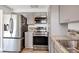 Modern kitchen featuring stainless steel appliances, stylish gray cabinets, backsplash, and hardwood floors at 5755 Oxalis Rd, Venice, FL 34293