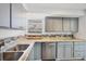 Kitchen with gray cabinetry, modern appliances, granite countertops, backsplash, and hardwood flooring at 5755 Oxalis Rd, Venice, FL 34293