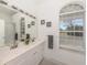 Bright bathroom featuring a double sink vanity, a large mirror, and a view to the exterior at 5931 Plover Rd, Venice, FL 34293