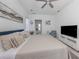 Comfortable main bedroom features an upholstered bed, ceiling fan, and wall-mounted television at 5931 Plover Rd, Venice, FL 34293