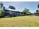 Backyard featuring a large screened in porch, a spacious lawn, and mature tropical landscaping at 610 Alligator Dr, Venice, FL 34293