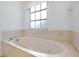 Bathroom with a large soaking tub, window, and neutral-colored tile surround at 610 Alligator Dr, Venice, FL 34293