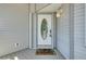 Charming front door with decorative glass and welcome mat on the porch of a light gray home at 610 Alligator Dr, Venice, FL 34293