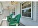 A cozy front porch with green rocking chairs, ceiling fans, and natural light from large windows at 610 Alligator Dr, Venice, FL 34293