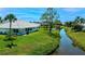 Serene backyard featuring a lush lawn and tranquil pond view with mature tropical landscaping at 611 Paget Dr, Venice, FL 34293