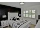 Stylish bedroom with black accent wall, white furniture, and a window with plantation shutters at 611 Paget Dr, Venice, FL 34293