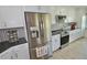 Kitchen featuring stainless appliances, granite counters, white cabinets, and laminate flooring at 611 Paget Dr, Venice, FL 34293