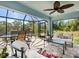 Inviting screened lanai featuring comfortable seating, a ceiling fan, and outdoor dining area at 6126 Spinnaker Blvd, Englewood, FL 34224