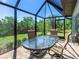 Enclosed patio with glass table and chairs offers relaxing outdoor living with a beautiful view of the backyard at 6126 Spinnaker Blvd, Englewood, FL 34224