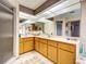 Bathroom with a large mirror, oak cabinets, long countertop, and a door to a shower at 617 Bonito Ave, Nokomis, FL 34275