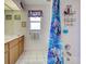 Bright bathroom with tile flooring, wood cabinets, and shower with decorative curtain at 617 Bonito Ave, Nokomis, FL 34275