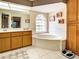 Bright bathroom featuring a soaking tub, double vanity, and linen closet, all with neutral tile and wood accents at 617 Bonito Ave, Nokomis, FL 34275