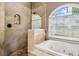Bathroom showcasing a natural stone walk in shower and soaking tub with jets at 6824 283Rd E St, Myakka City, FL 34251