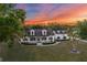 Stunning white home with black shutters and a large lawn against a vibrant sunset sky at 6824 283Rd E St, Myakka City, FL 34251