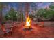 Outdoor fire pit with flames and seating in a tranquil wooded setting at twilight at 6824 283Rd E St, Myakka City, FL 34251