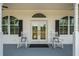 Close-up of the front porch with double doors and rocking chairs creating a warm, inviting atmosphere at 6824 283Rd E St, Myakka City, FL 34251